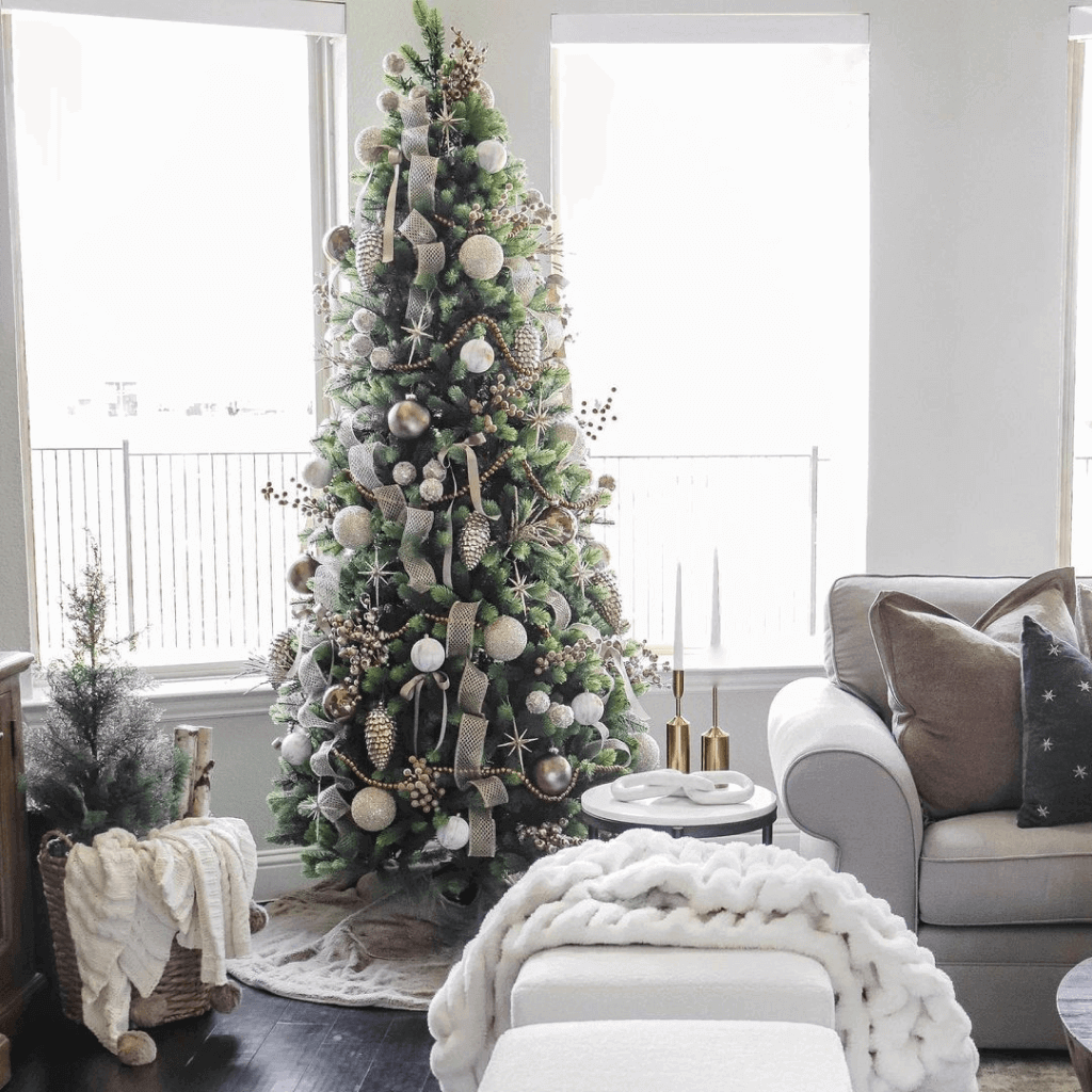 12 ft Royal Fir Slim artificial Christmas tree, pre-lit with warm white and multicolor LED lights, decorated in a white living room beside a gray sofa