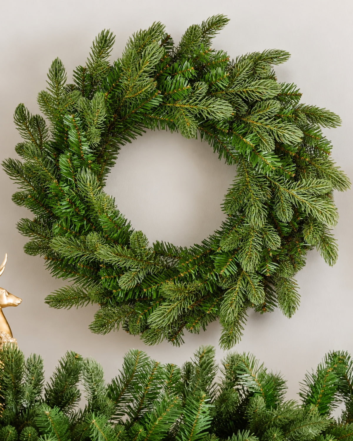 24 in Cypress Spruce artificial Christmas wreath, unlit, above a matching garland on a white wall