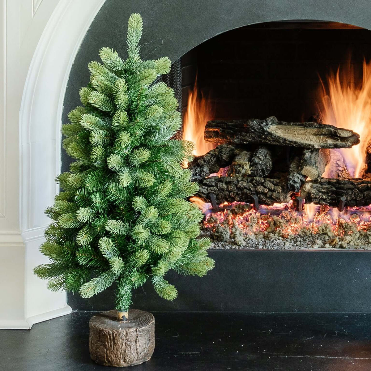 3 ft Royal Fir tabletop artificial Christmas tree, pre-lit with warm white LED lights, beside a stone fireplace