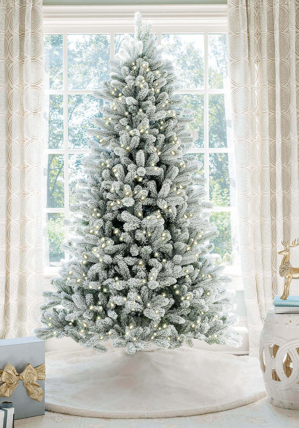 7.5 ft King Flock artificial Christmas tree, glowing with warm white lights in front of a large window