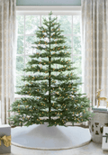 7.5 ft Rushmore Fir artificial Christmas tree, glowing with warm white LED lights in front of a large window