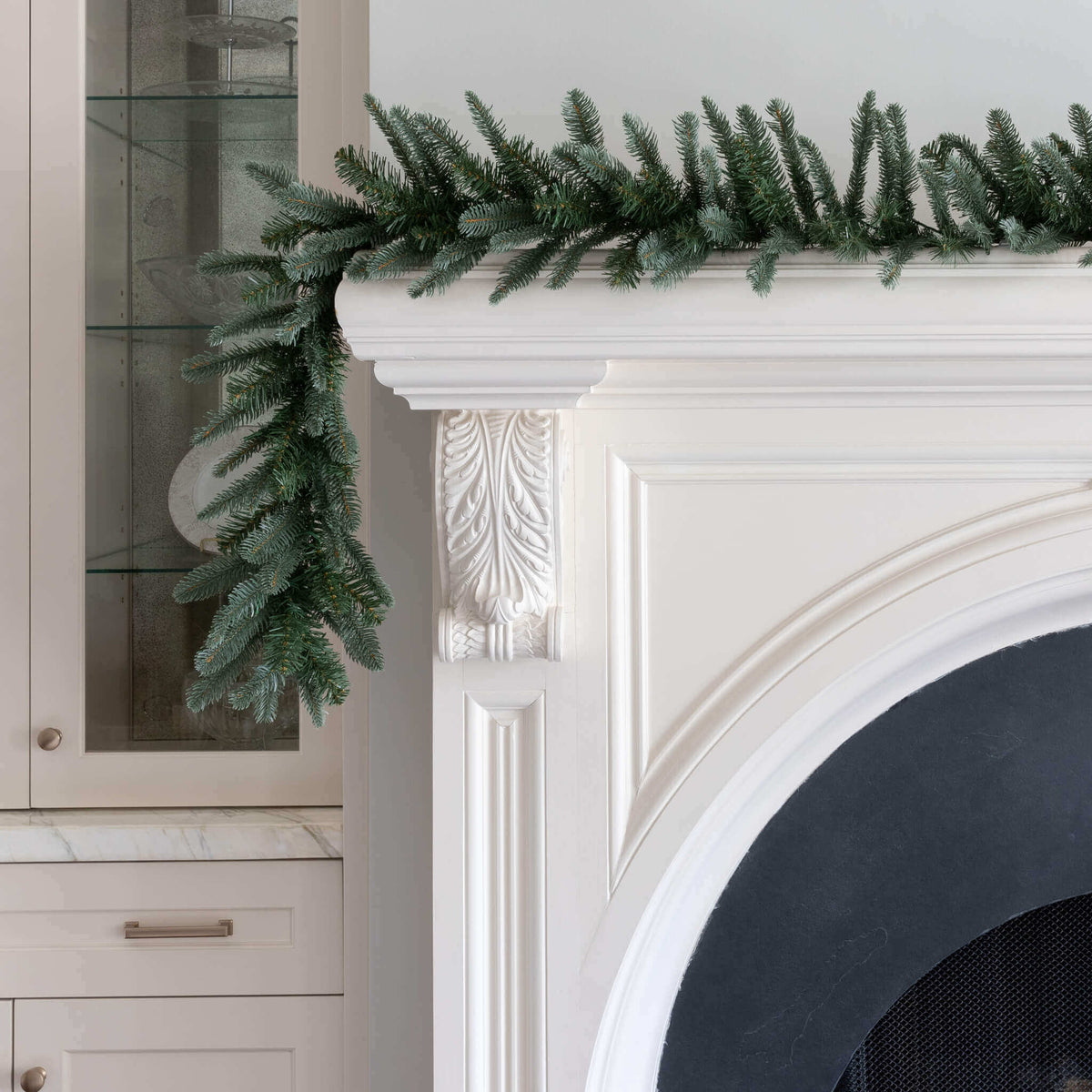 King Noble Fir artificial Christmas garland draped over a white fireplace mantel