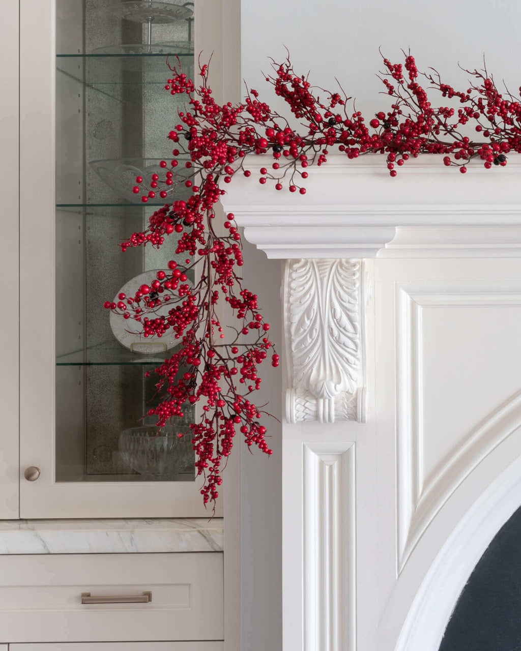 9 ft Berry artificial Christmas garland, unlit, with red berries draped over a white fireplace mantel