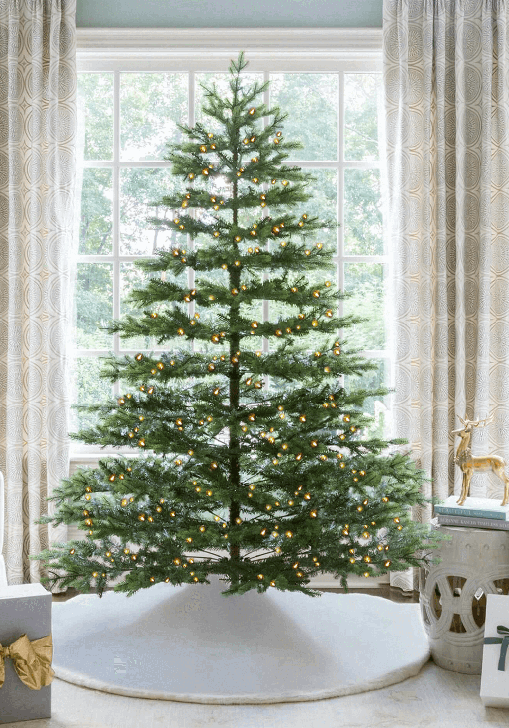 9 ft Rushmore Fir artificial Christmas tree, glowing with warm white LED lights in front of a large window