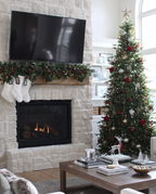 Alpine Fir Slim artificial Christmas tree, decorated beside a white stone fireplace in a living room