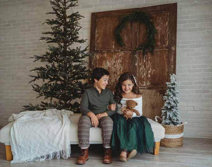 Two children on a bench beside slim green trees, King of Christmas customer photo by @georgescuphotography