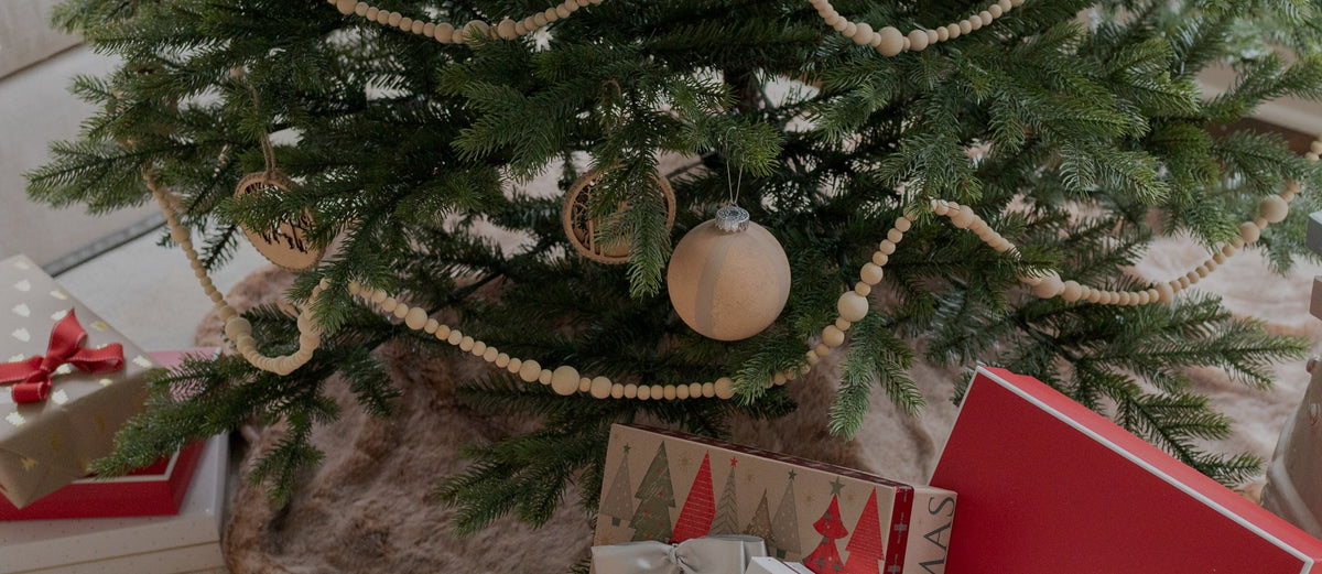 Decorated artificial Christmas tree with a wood bead garland and wrapped gifts underneath