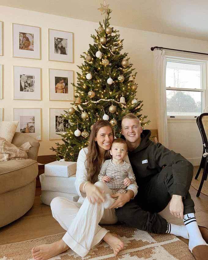 Couple with a baby on the floor beside a tree, King of Christmas customer photo by @kmcbaindesign