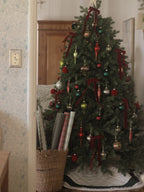 Cypress Spruce artificial Christmas tree, decorated with red ornaments beside bookshelves