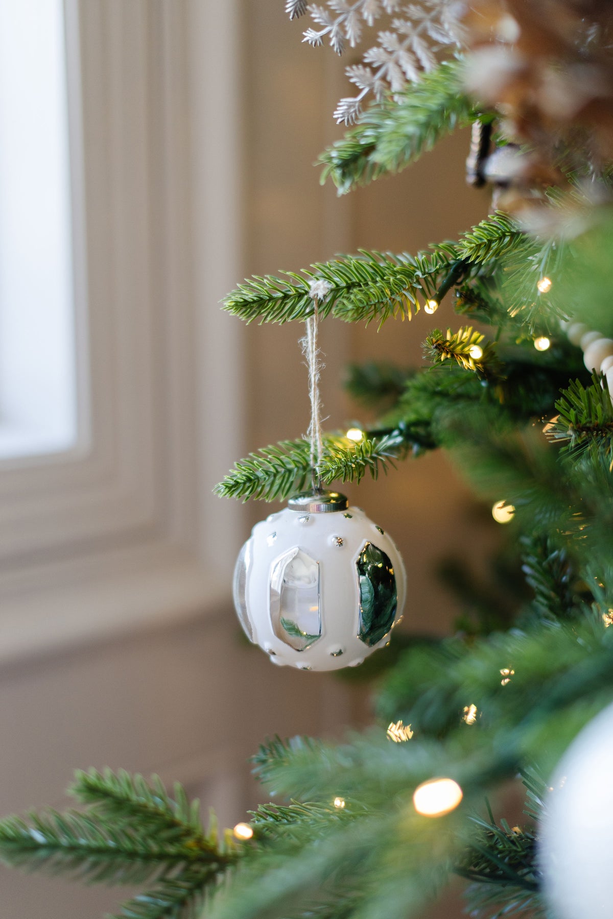 King of Christmas Distressed White Glass Ornament Set (6 Pack) on a decorated Christmas tree