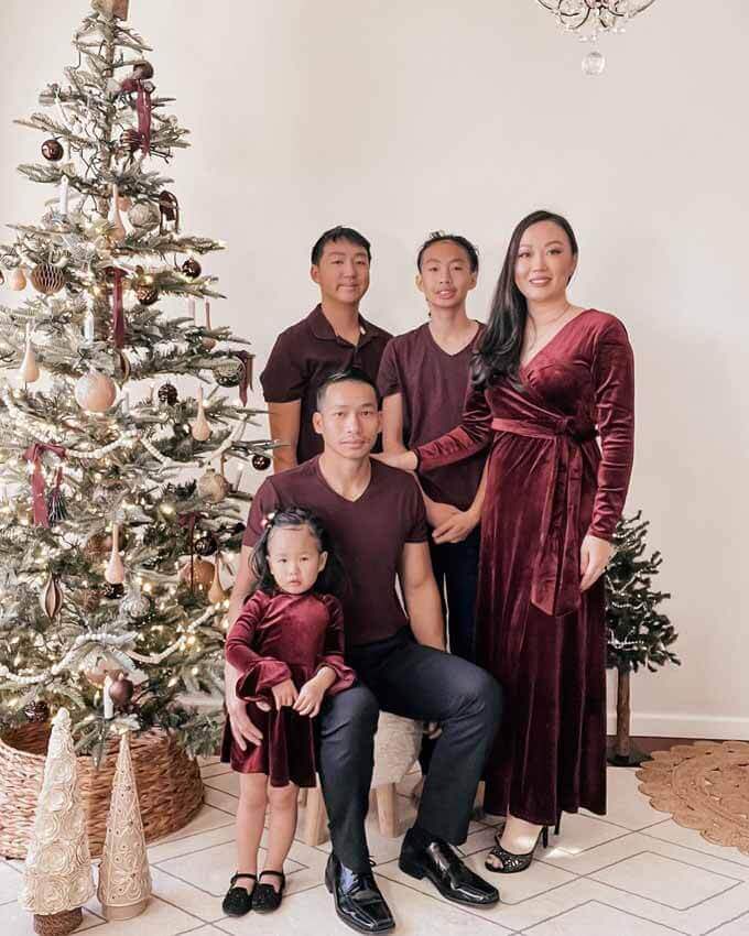 Family in burgundy outfits beside a flocked tree, King of Christmas customer photo by @my_lil_amethyst