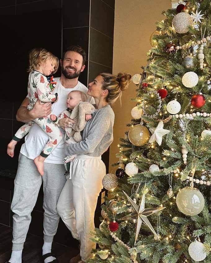 Family holding a child beside a decorated tree, King of Christmas customer photo by @bridgetlaurenh
