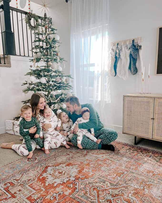 Family on a rug beside a green tree, King of Christmas customer photo by @angiebetzsold