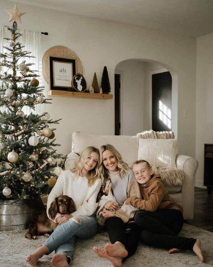 Family seated beside a slim flocked tree, King of Christmas customer photo by @amandaw818