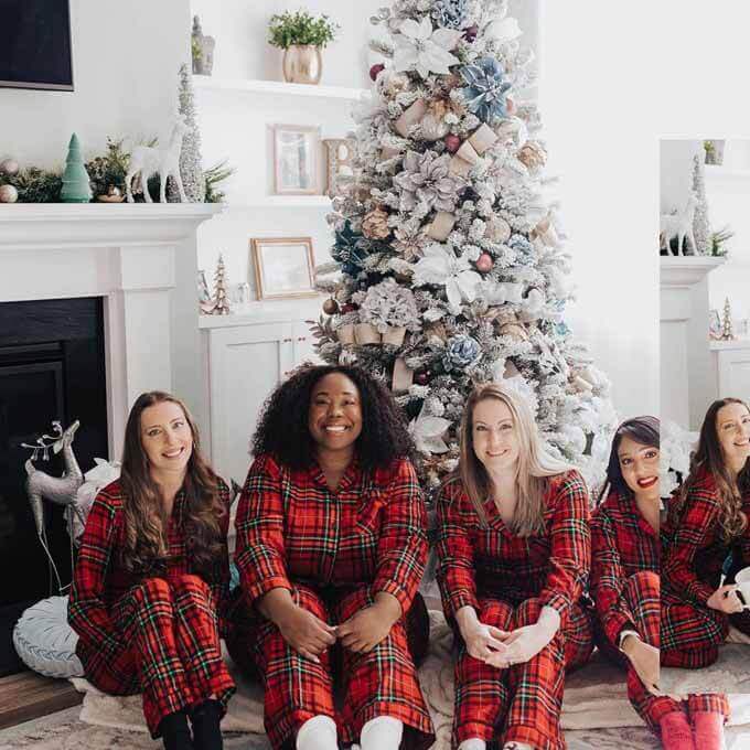 Four women in red plaid pajamas by a flocked tree, King of Christmas customer photo by @itsbellmade