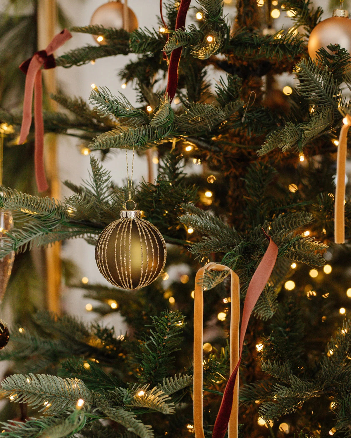 Gold glass ornaments and velvet ribbon on a pre-lit artificial Christmas tree