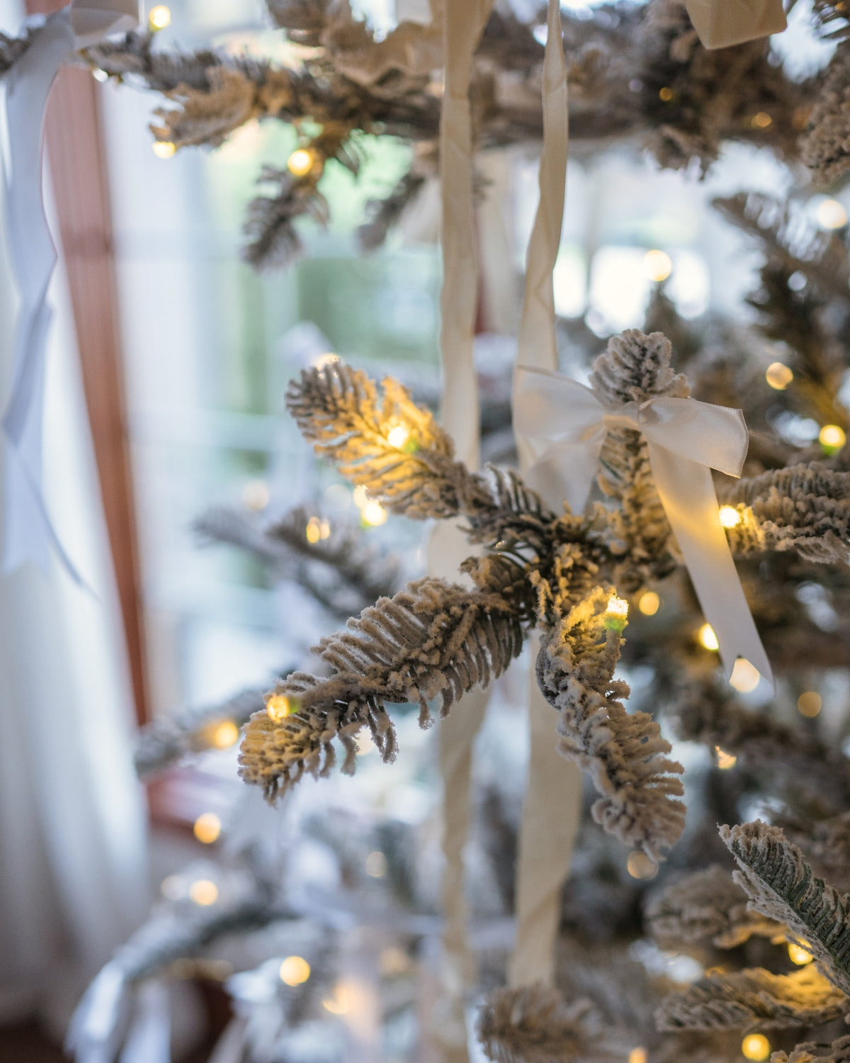 Close-up of the King Noble Flock artificial Christmas tree's flocked tips glowing with warm white LED lights