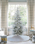 9 ft King Noble Flock artificial Christmas tree, glowing with warm white LED lights in front of a large window