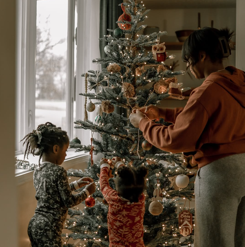 Mother and children decorating a flocked tree by a window, King of Christmas customer photo by @gracefullyfitmama