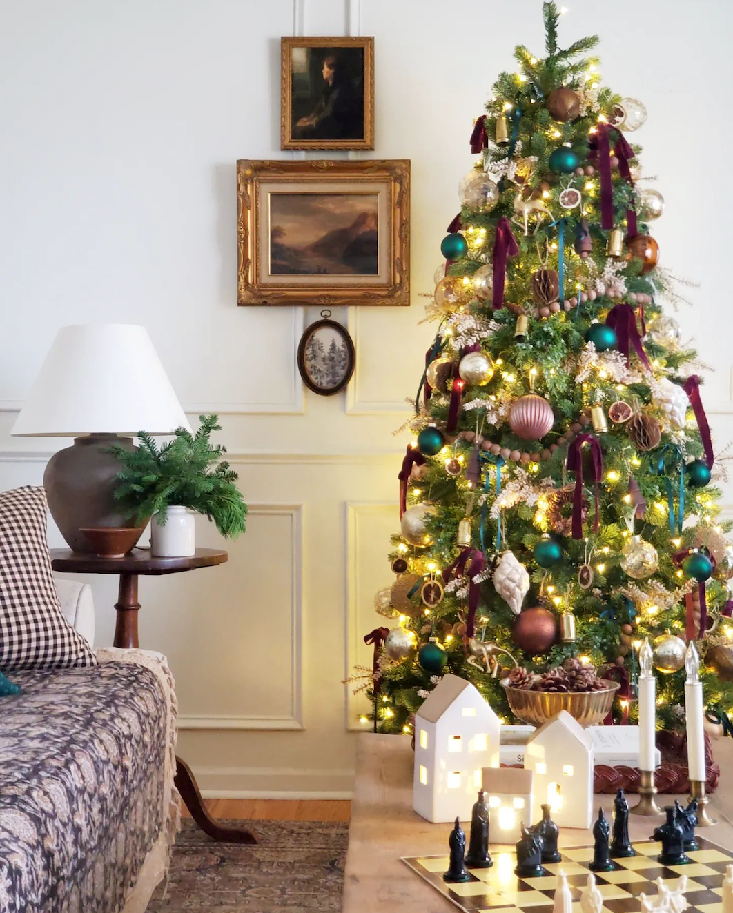 Royal Fir Slim artificial Christmas tree, decorated and glowing beside a portrait painting