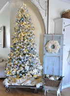 7.5 ft King Flock artificial Christmas tree, pre-lit with warm white LED lights, decorated beside a light blue cabinet