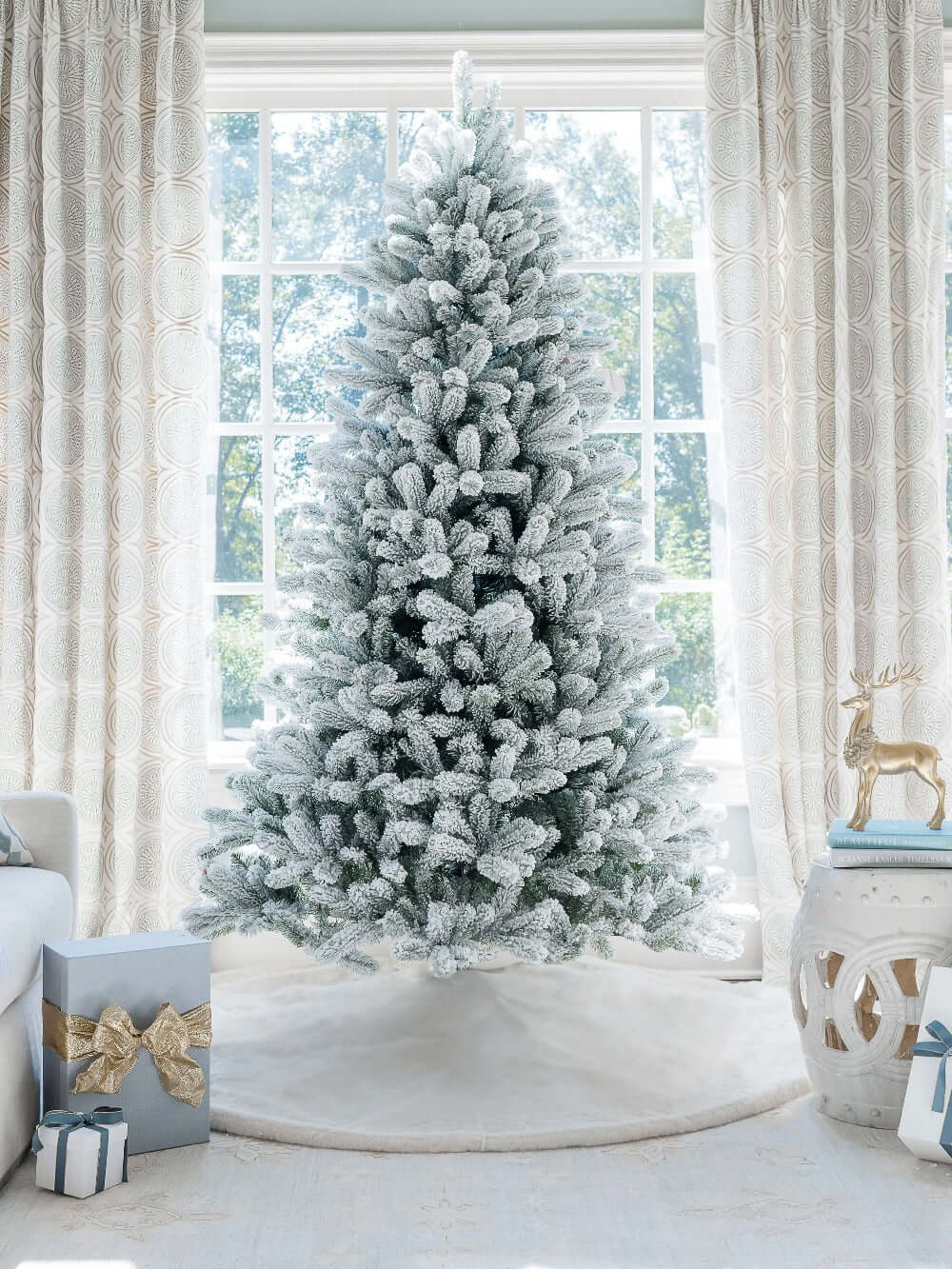 7.5 ft King Flock artificial Christmas tree, standing in front of a large window with a white tree skirt