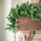 9 ft Cypress Spruce artificial Christmas garland, pre-lit with warm white LED lights, draped over a stone fireplace mantel