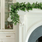 9 ft Cypress Spruce artificial Christmas garland, pre-lit with warm white LED lights, draped over a white fireplace mantel
