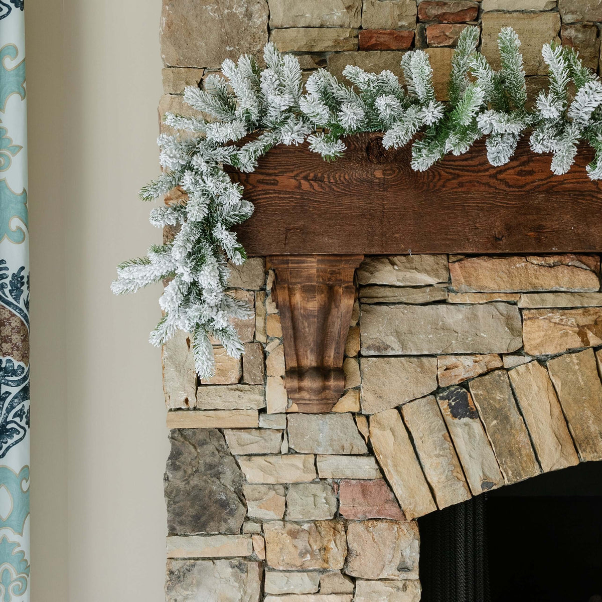 King Flock artificial Christmas garland draped over a rustic stone fireplace mantel
