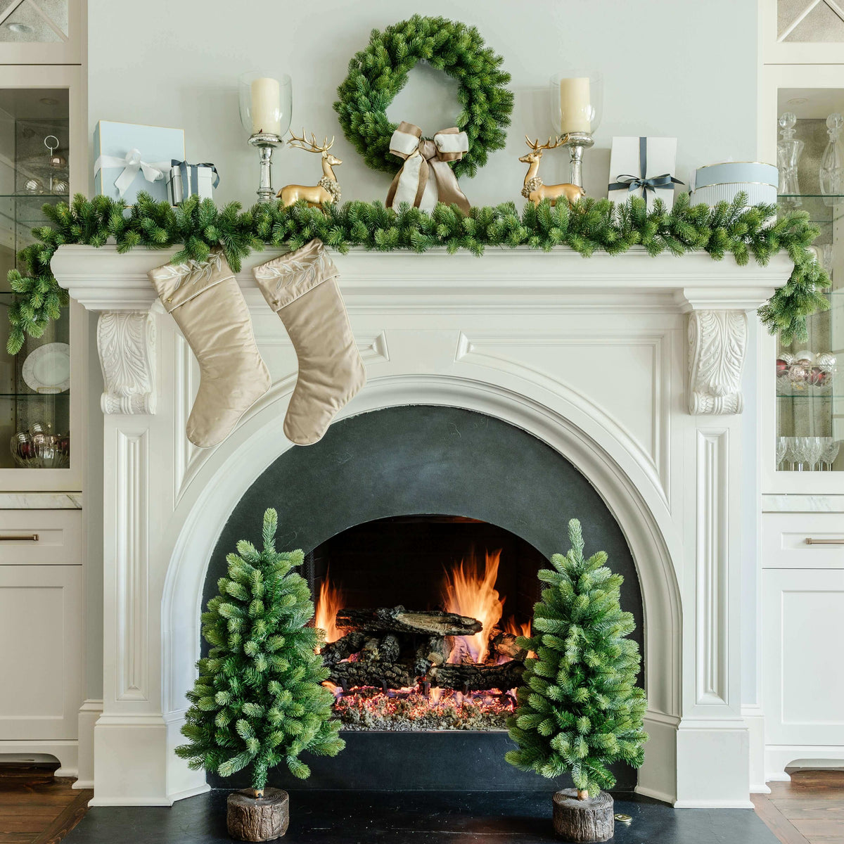 Royal Fir wreath, garland and tabletop trees on a white fireplace with stockings